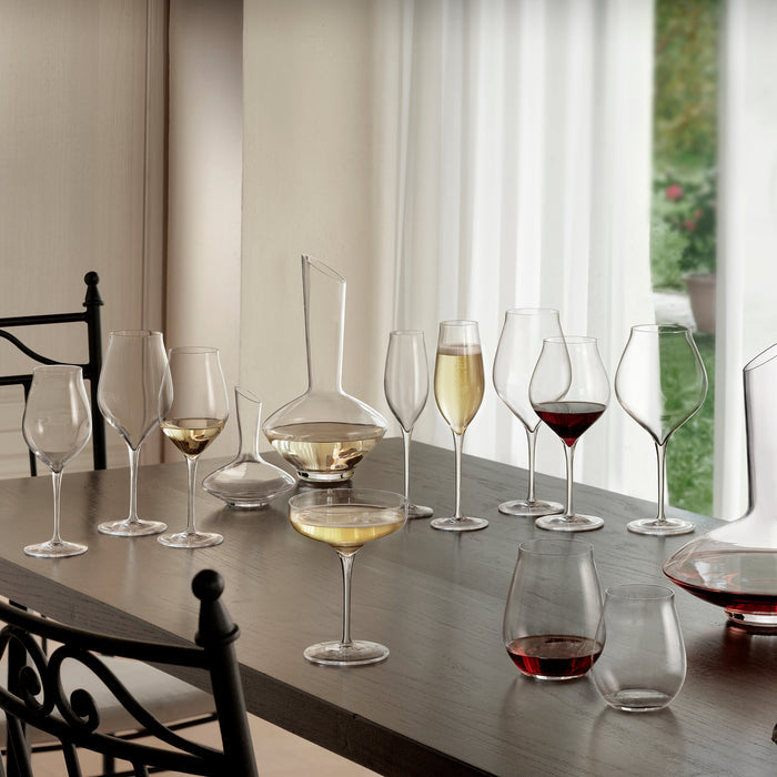 Full Vinea collection of various size and shape glasses and decanters, filled with wine of empty, standing on a wooden table in a dining room