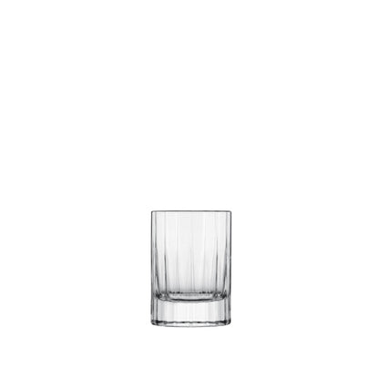 A clear, faceted, round, retro-style Bach shot glass with a thick base.