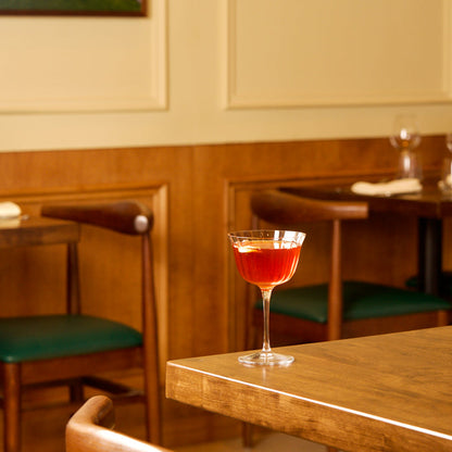 Bach Retro Fizz Cocktail glass with red liquid on a wooden table in a bar setting