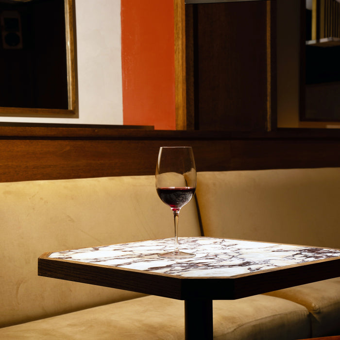 Crescendo Bordeaux Red Wine Glass filled with red wine on a marble table and a colorful background