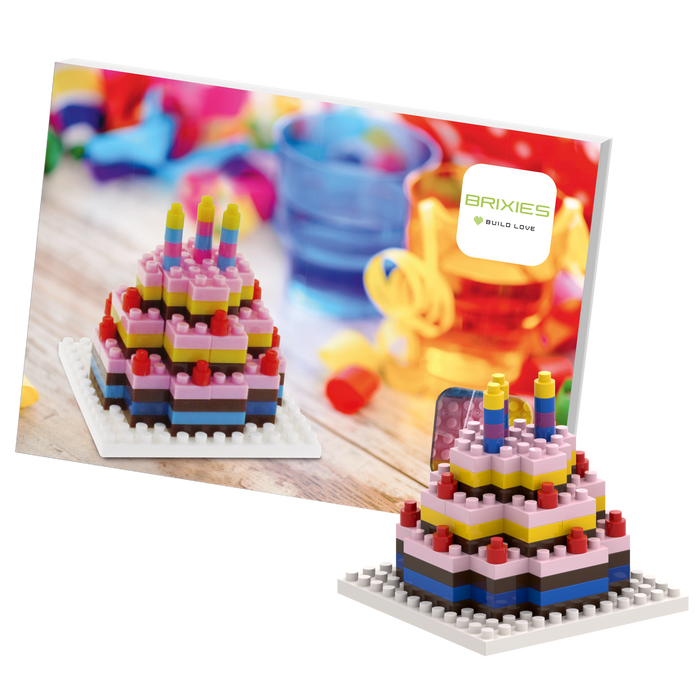 The Brixies Postcard Birthday Cake is a colorful mini toy brick model with candles, shown in front of its box featuring the Brixies logo. This build kit is a unique greeting card you can mail for birthdays.