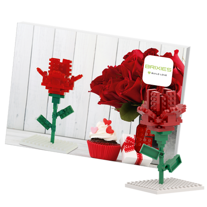 A photo shows the Brixies Postcard Flower, a LEGO-style 3D rose model, standing before a card with real red roses, a heart-decorated cupcake, and a ribboned gift box. The card features the Brixies Build Love logo.