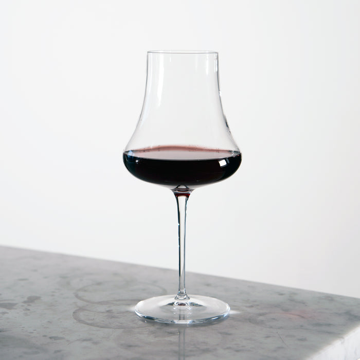 Tentazioni Bordeaux Red Wine Glass filled with red wine standing on a light marble surface and a white background