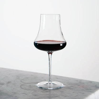 Tentazioni Bordeaux Red Wine Glass filled with red wine standing on a light marble surface and a white background