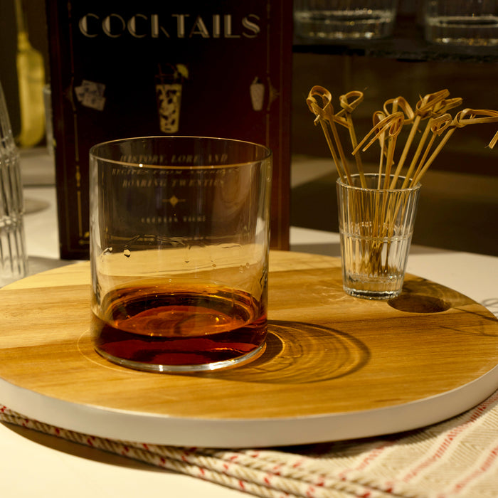 Top Class DOF glass filled with whisky, standing on a wooden tray with décor in the background