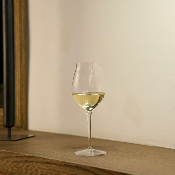 Vinea Malvasia wine glass filled with white wine on a wooden surface and a ivory background