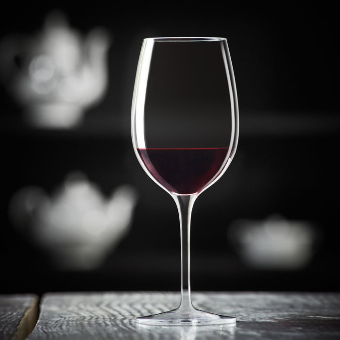 Vinoteque Ricco Red Wine Glass filled with red wine standing on a wooden surface and a black background