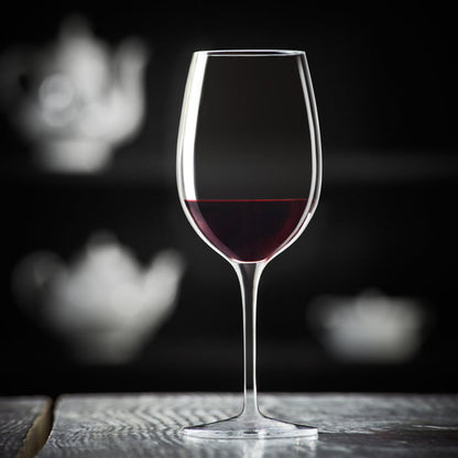Vinoteque Ricco Red Wine Glass filled with red wine standing on a wooden surface and a black background