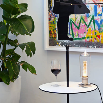 Vinoteque Riserva Red Wine Glass filled with red wine standing on a small white table next to a modern lamp, colorful graffiti painting and a plant in the background